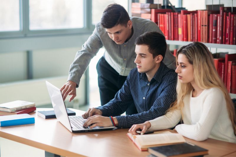 Young people sitting around a laptop chatting